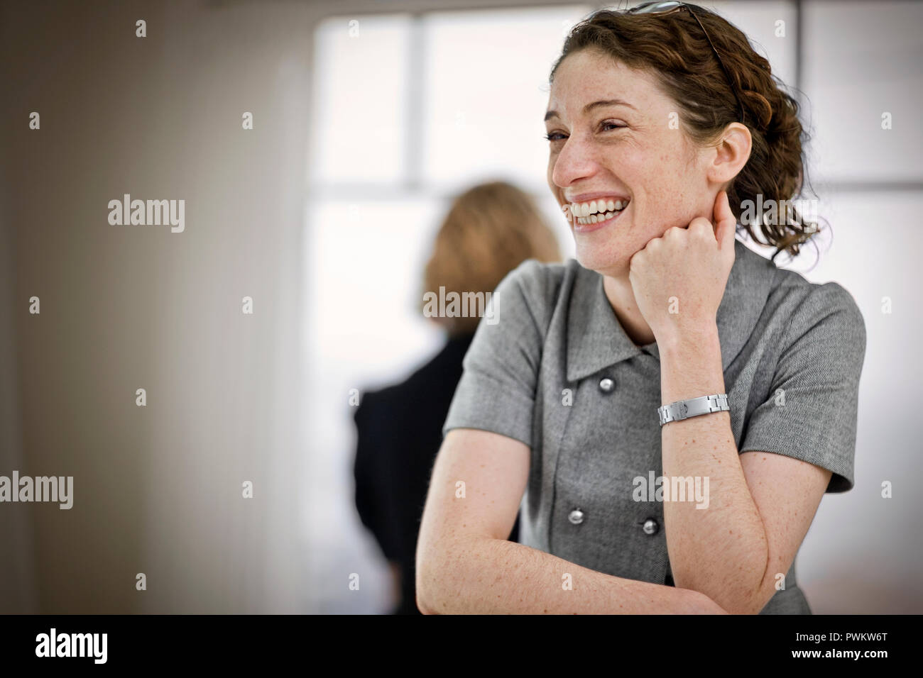 Lachende junge Frau ihr Kinn auf ihre Hand. Stockfoto