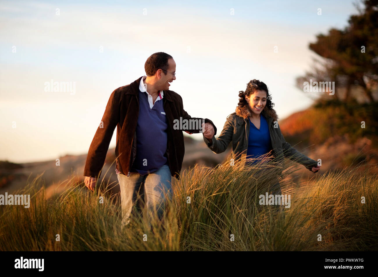 Gerne Mitte nach paar Hände halten während man durch langes Gras. Stockfoto