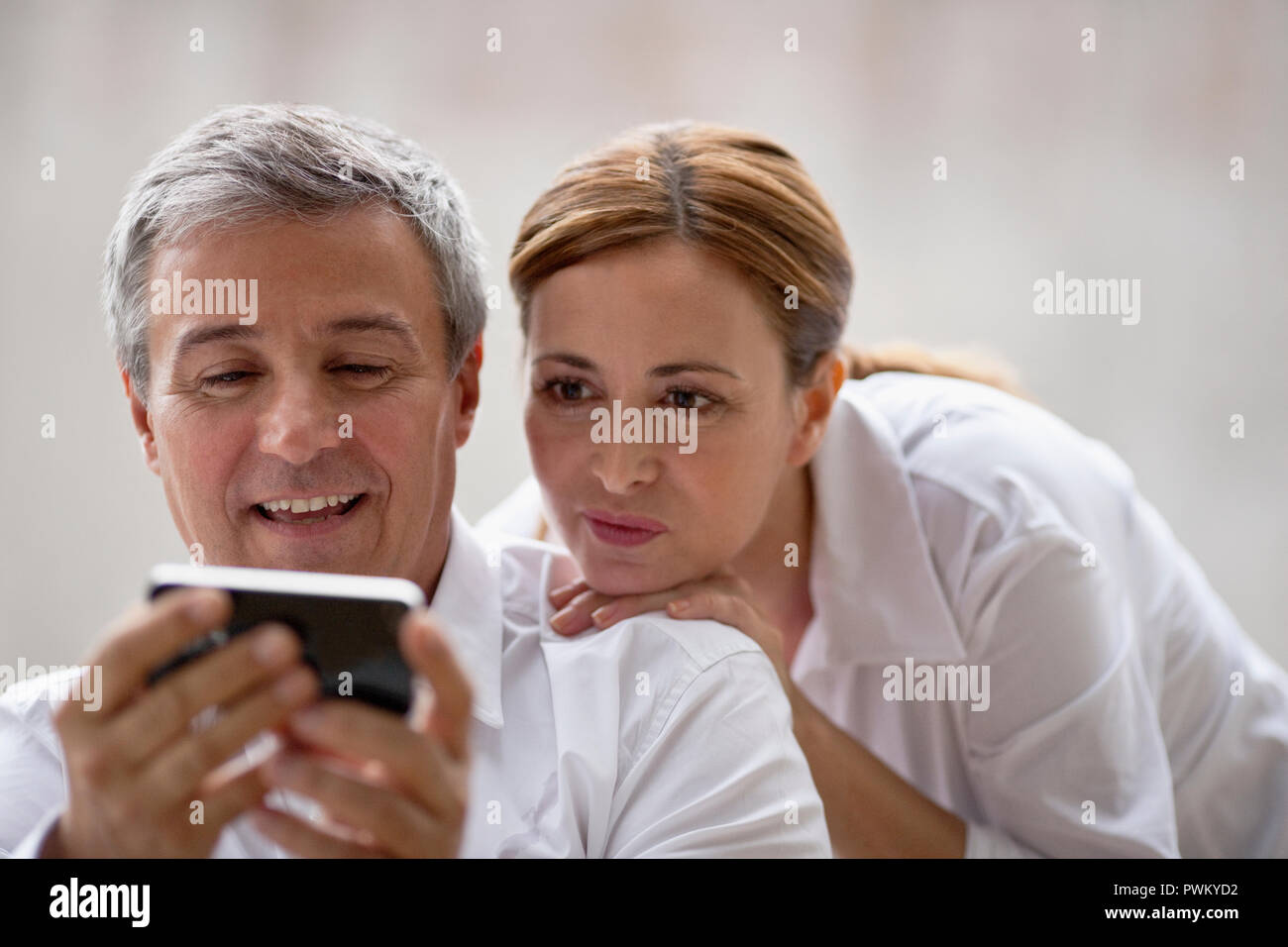 Professionelles Ehepaar, das sich etwas auf einem iphone suchen. Stockfoto