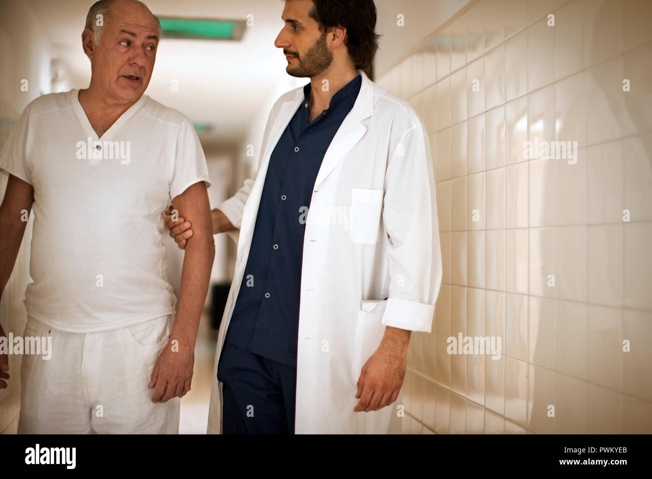 Ältere Menschen zu Fuß ein Krankenhaus Flur mit seinen Doktor. Stockfoto