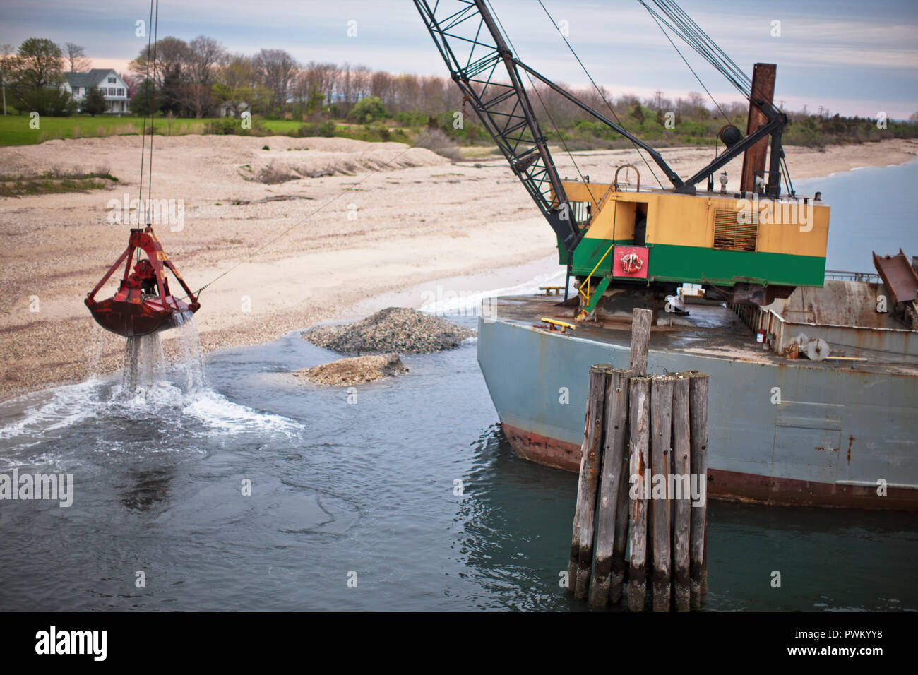 Kran auf einem Boot heben Sie die Rückstände aus der Küstenlinie. Stockfoto