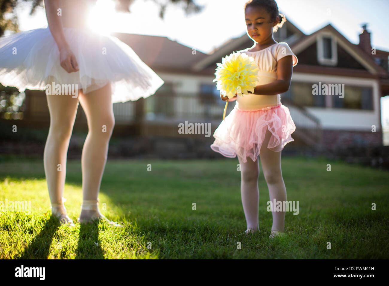 Glückliche junge Mädchen spielen mit ihrer Mutter in ihrem Hinterhof. Stockfoto