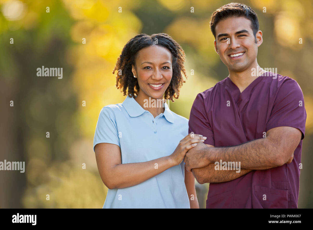 Porträt eines lächelnden männlichen und weiblichen Krankenschwester Seite an Seite in einem Park. Stockfoto