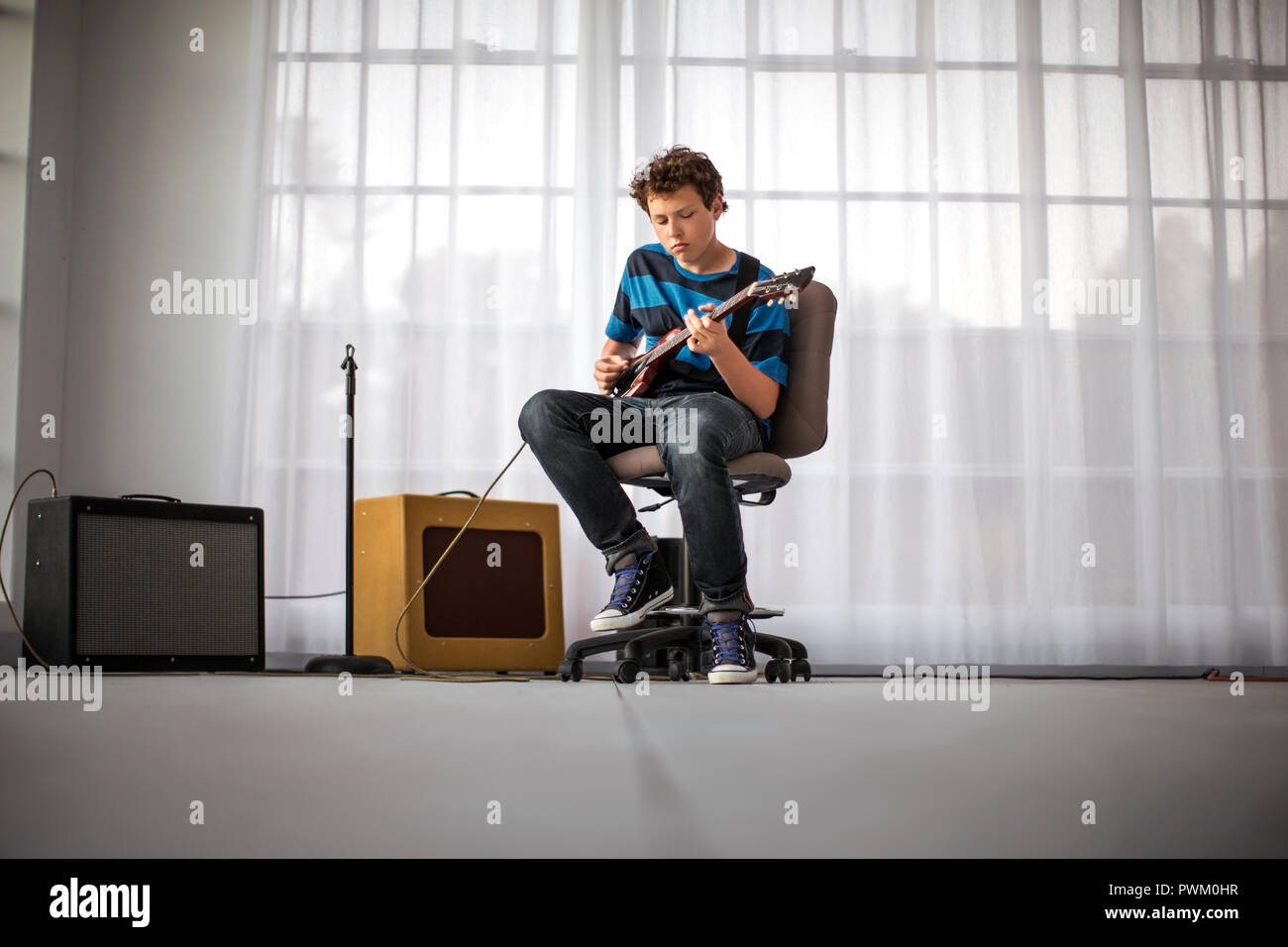 Teenager spielen E-Gitarre im Wohnzimmer. Stockfoto