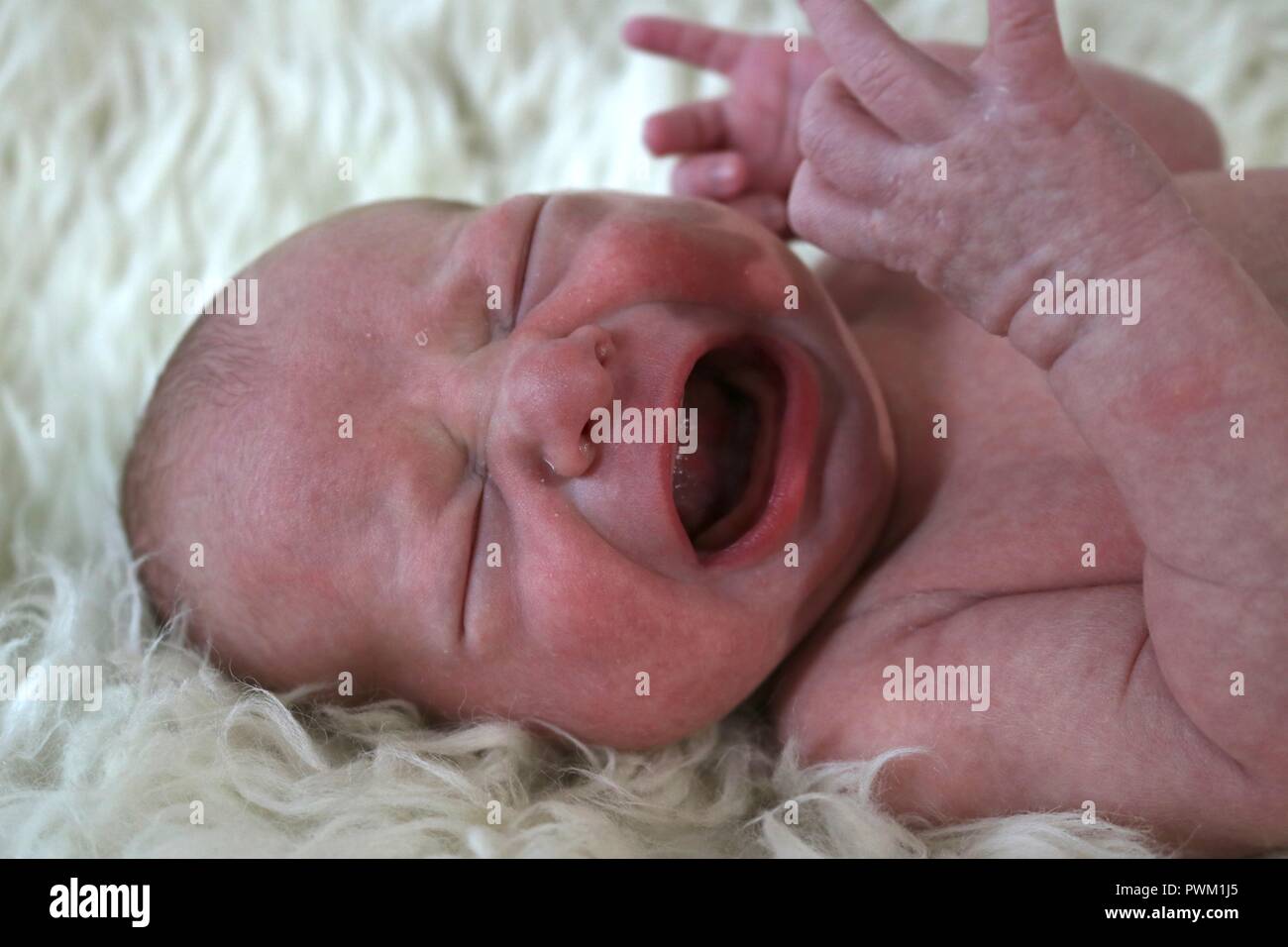 Neugeborenes Baby weinen auf einem weißen fuzzy Decke Stockfoto