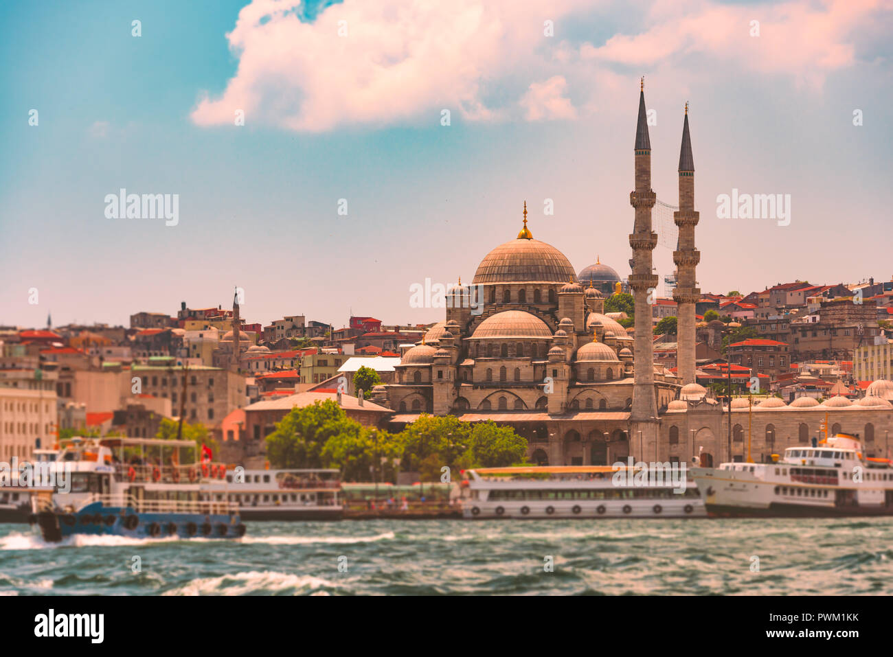 Yeni Cami Ottoman Imperial Moschee im Viertel Eminönü Istanbul, Türkei. Straße von Bosporus mit Schiffen, die in den Vordergrund und blauen bewölkten Himmel Stockfoto