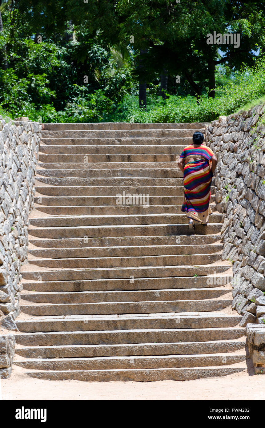 Indische Frau im Sari geht die Treppe hinauf, Verlassen der U-Shiva Tempel in Hampi, Karnataka, Indien. Stockfoto