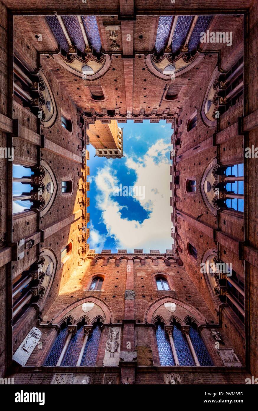 Siena ist eine unglaubliche, verwinkelten Stadt. Abgebildet ist der Innenhof der Cappella di Piazza, mit Blick auf den Turm von Mangia während eines Toskanischen Sommer. Stockfoto