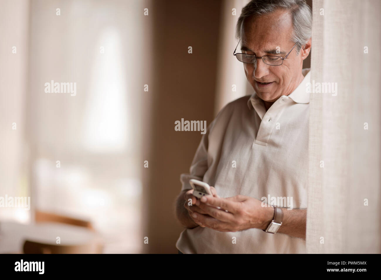 Älterer Mann mit Brille sieht, auf sein Handy. Stockfoto