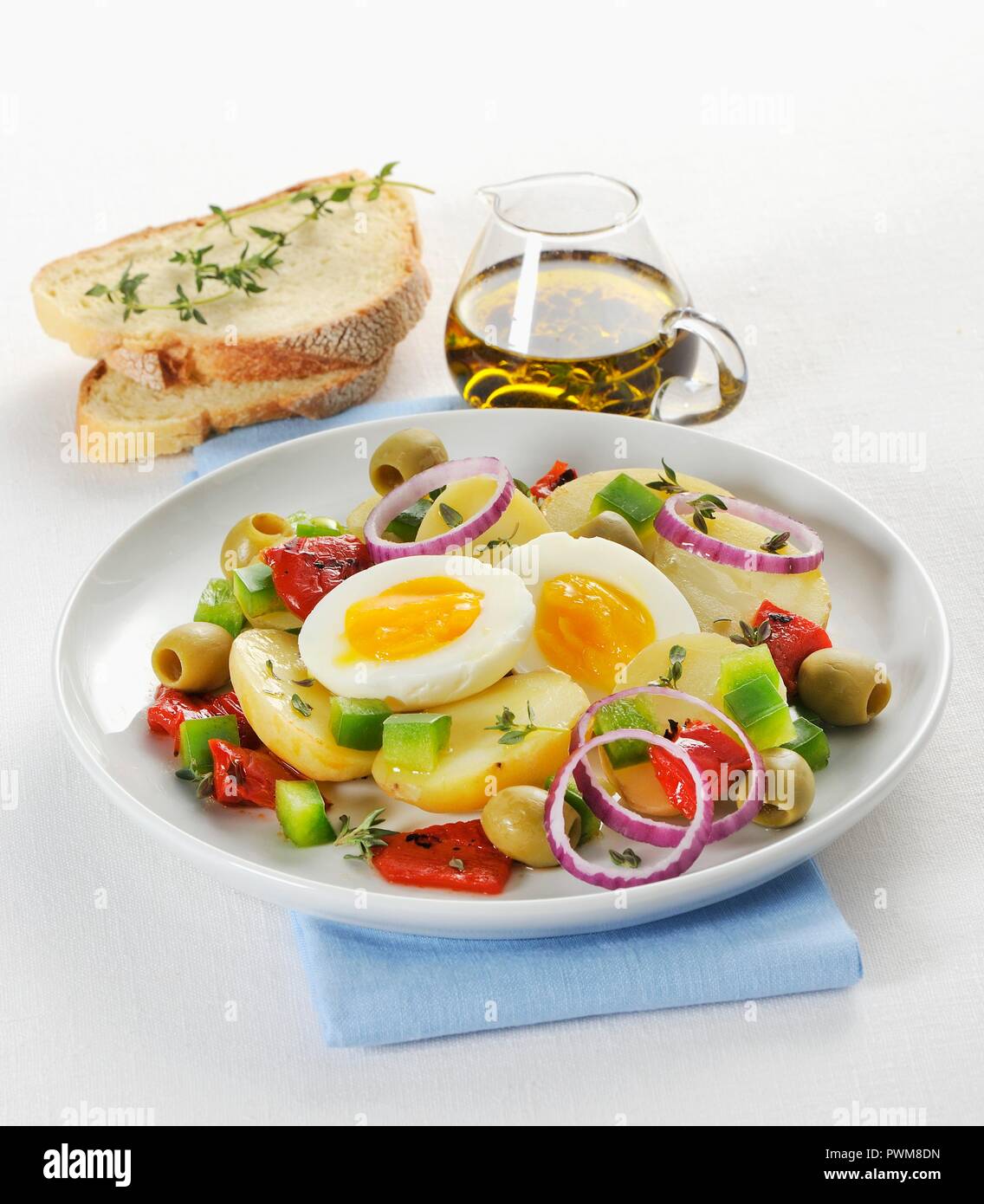 Warmer Kartoffelsalat mit Paprika, Oliven, Zwiebeln und ein weich gekochtes Ei Stockfoto