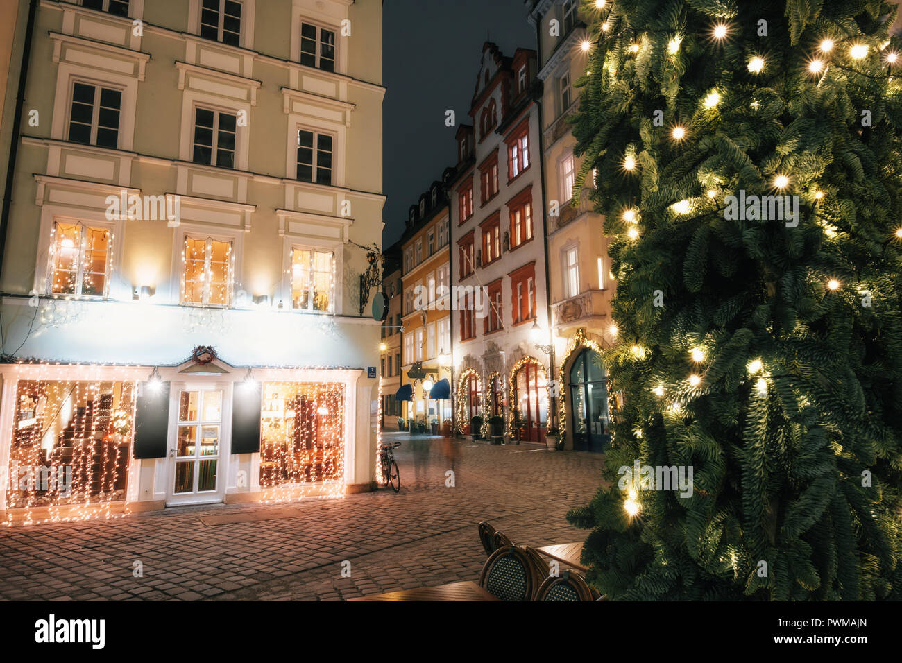 Verwischt die Menschen bewegt über beleuchtete Straße Platzl Square bei Nacht mit Weihnachtsbaum in München, Bayern, Deutschland Stockfoto