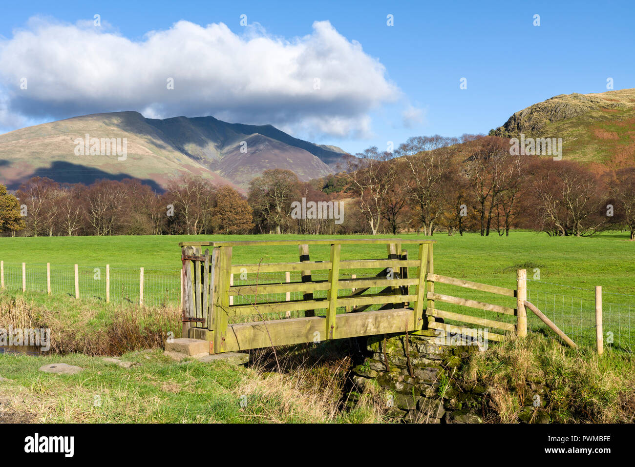 Ein Holzsteg über eine kleine Beck in der "Dale unten mit Blencathra jenseits im englischen Lake District National Park, Cumbria, England. Stockfoto