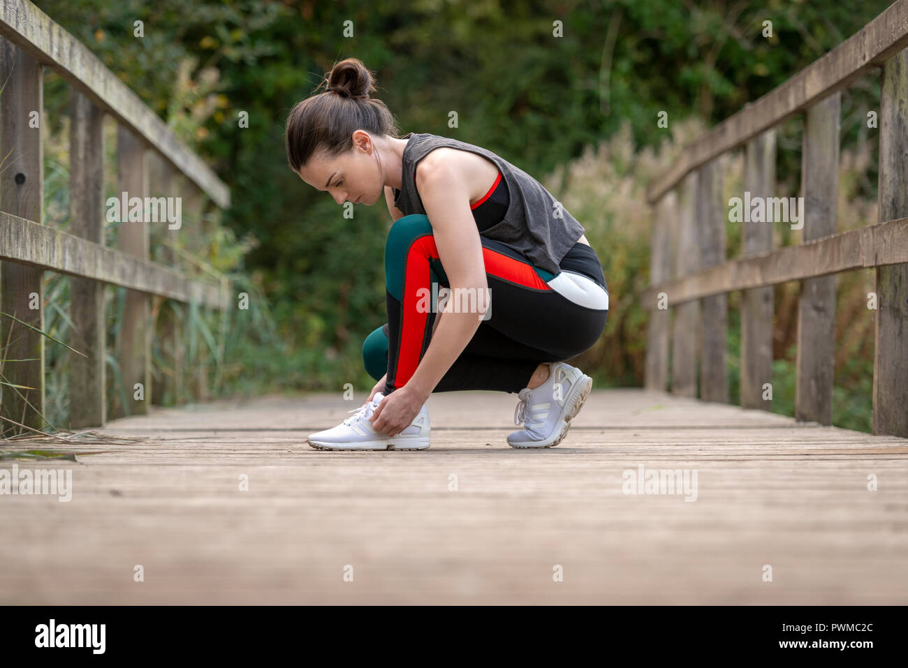 Sportliche Frau, die Band ihre Trainer vor Ausübung und Ausführen Stockfoto