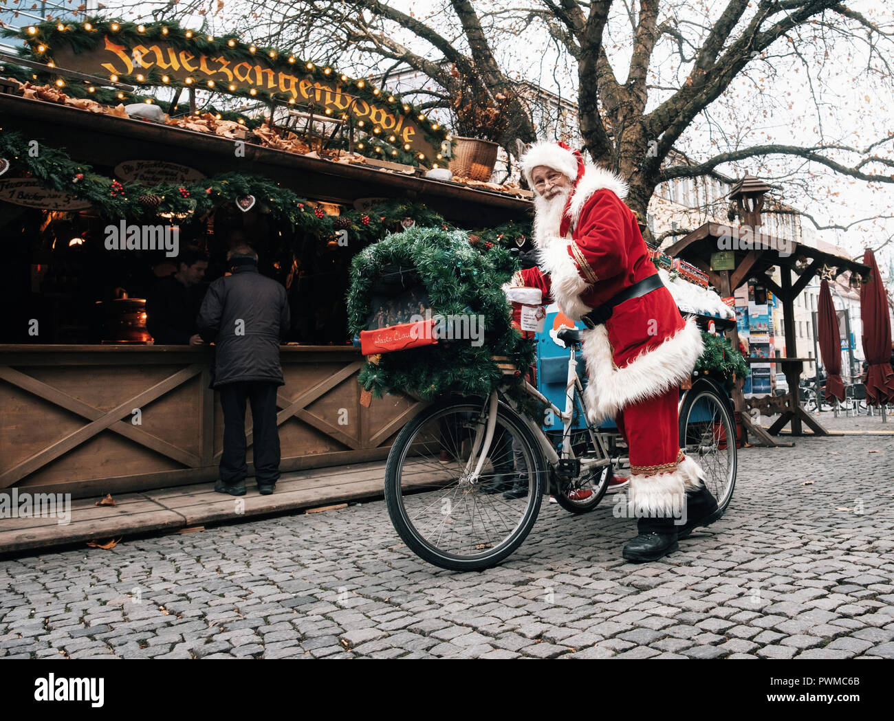 Munich, Bayern, Deutschland - Dezember 6, 2017: Santa Claus fährt ein eingerichtet Fahrrad mit Geschenken auf Weihnachtsmarkt Rindermarkt in München. Stockfoto