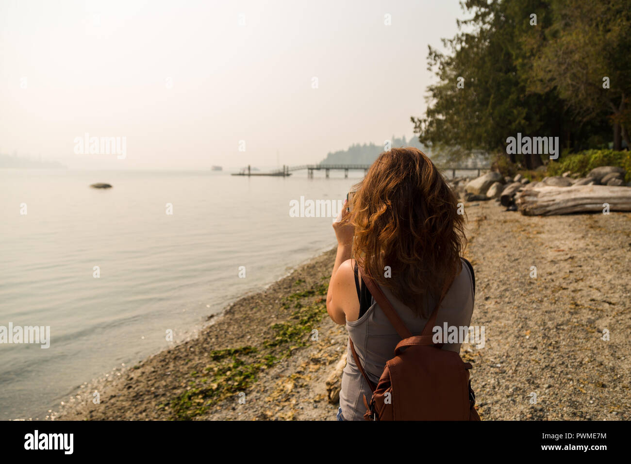 Eine brünette Frau nimmt ein Foto von der Dunst in der Umgebung von Vancouver 2018 Waldbrände. Stockfoto