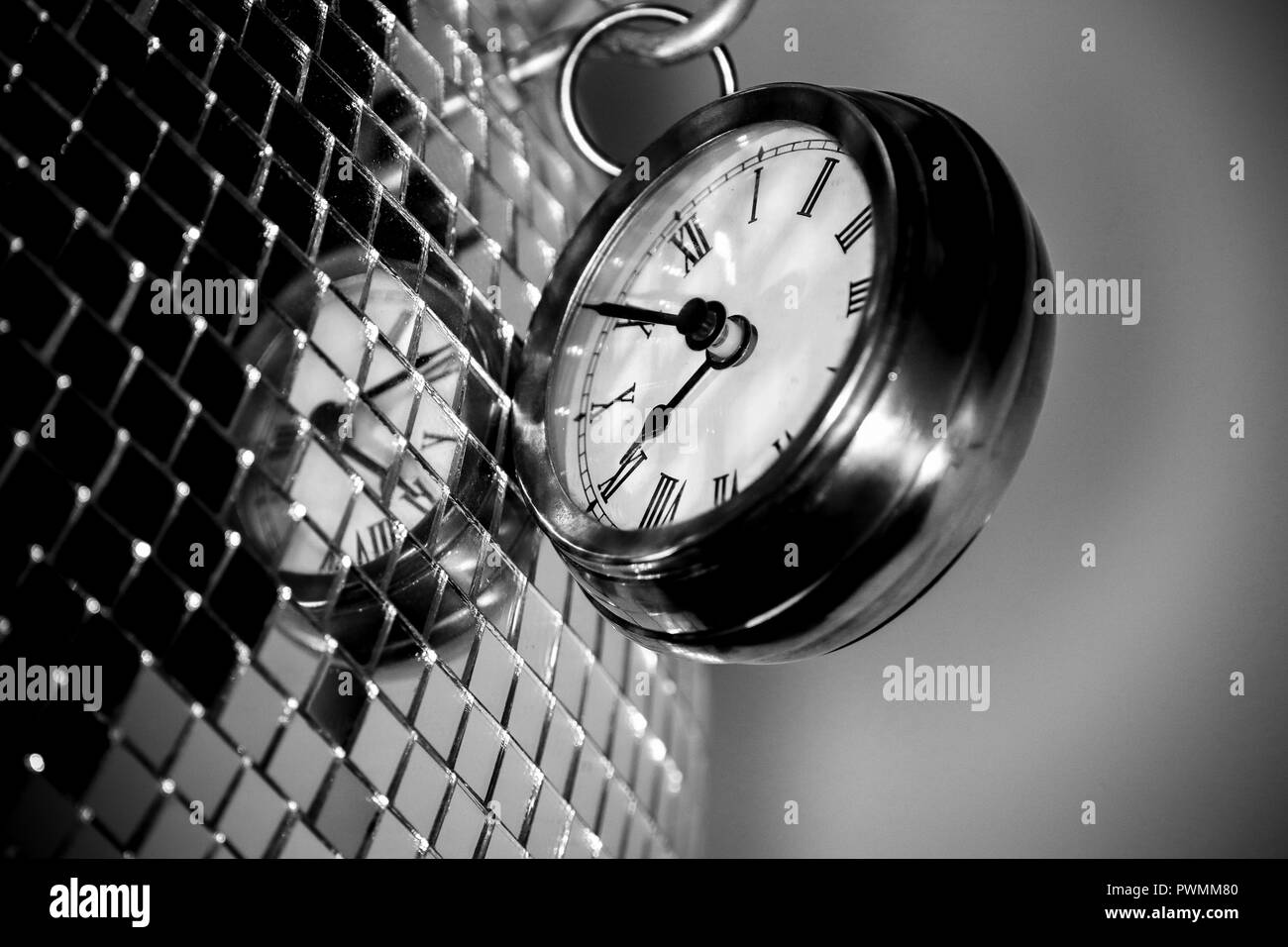 Close up arty Schuß eines Metall große Taschenuhr Uhr neben einem Silber Disco ball in Schwarz und Weiß Stockfoto