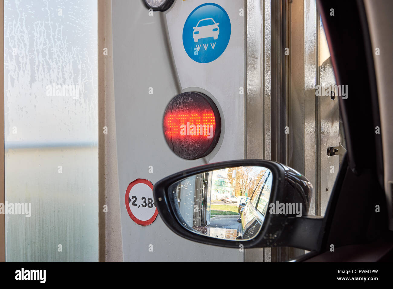 Nahaufnahme einer Rückspiegel im Auto waschen mit Wasser Tropfen, ein Symbol und ein rot leuchtendes Stop Schild an einer Ampel Stockfoto