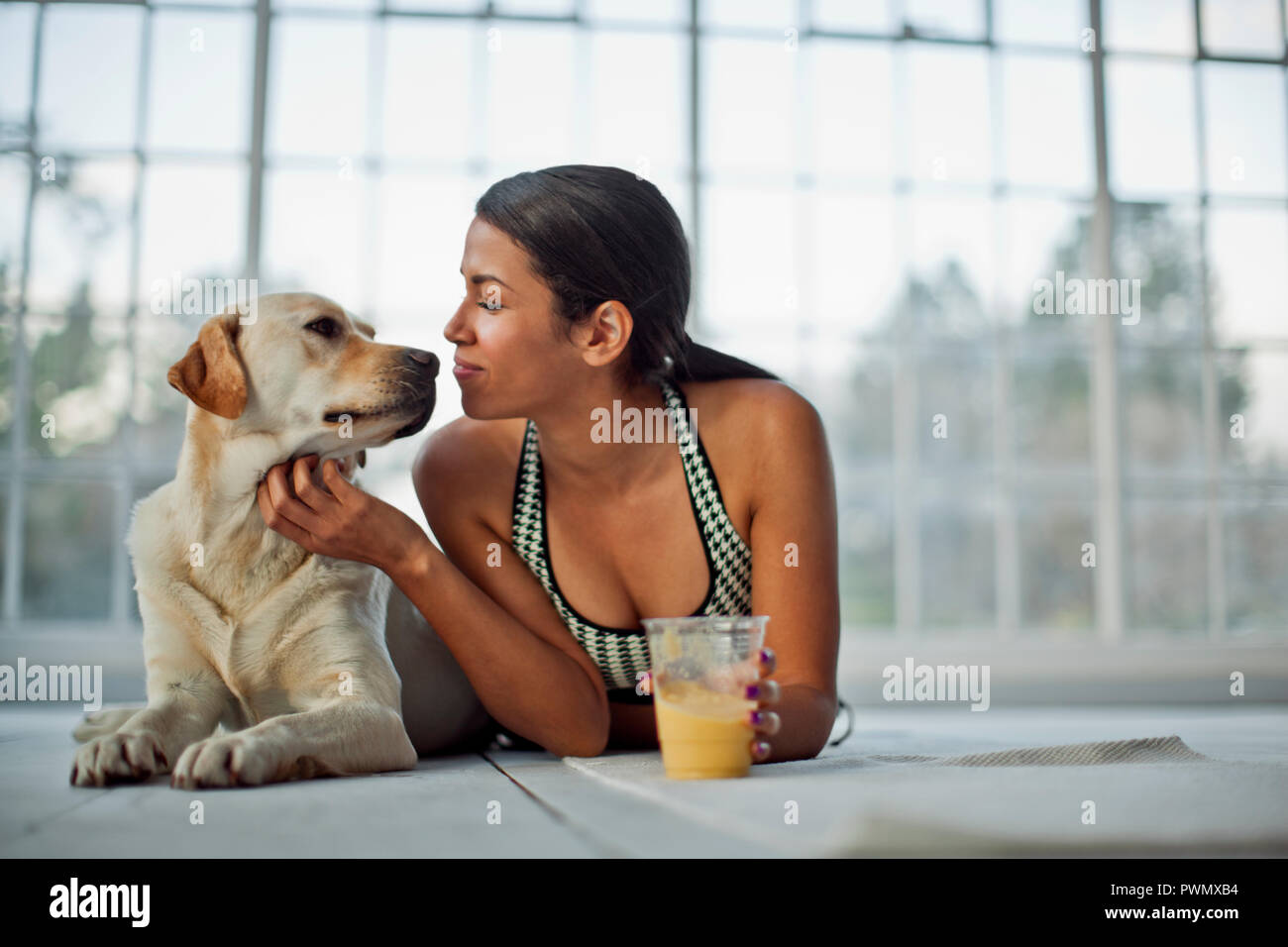 Junge Frau nuzzling Ihren Hund während rehydrating mit Saft. Stockfoto