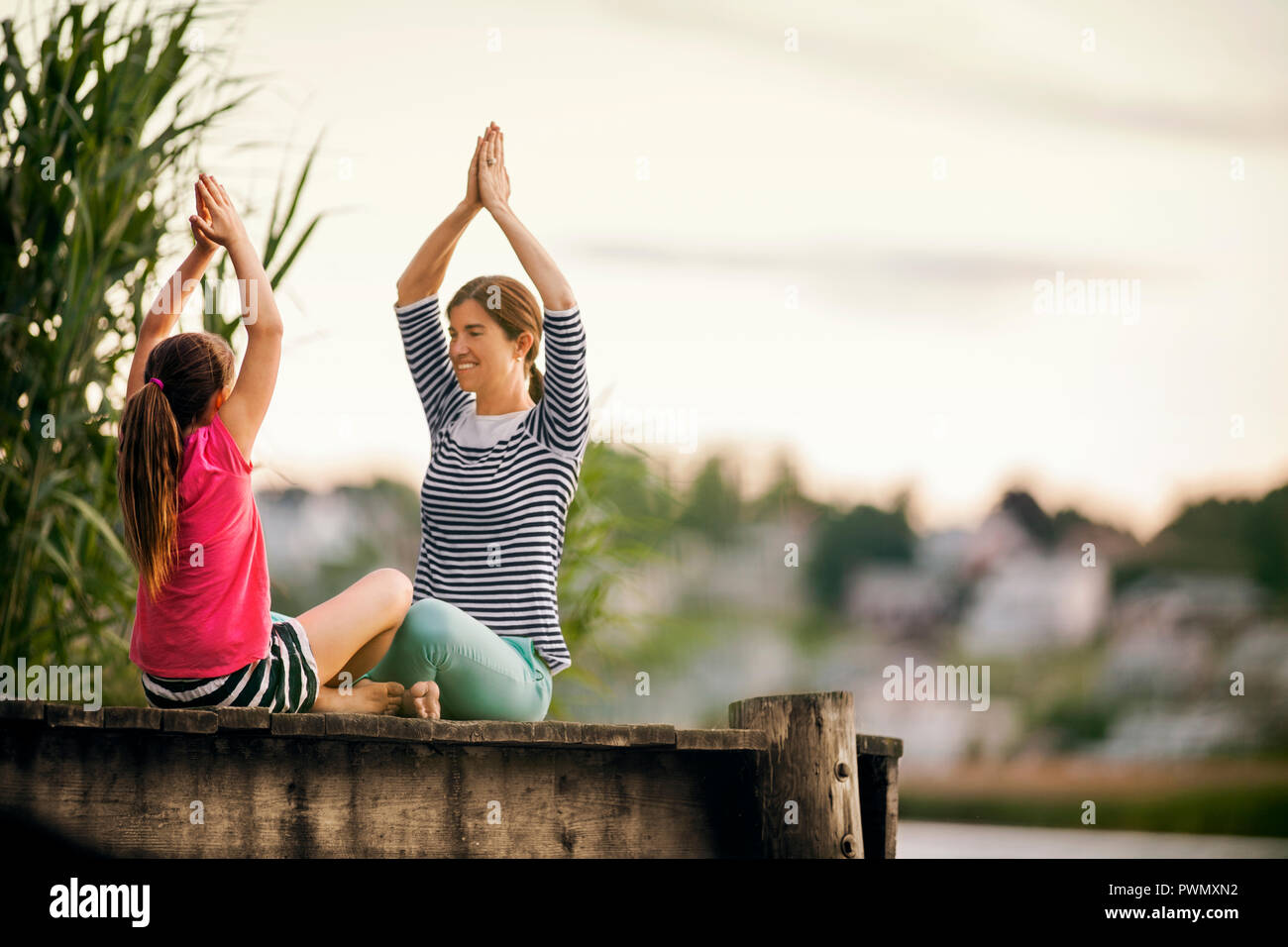 Mutter und Tochter Üben Yoga auf einem Pier. Stockfoto