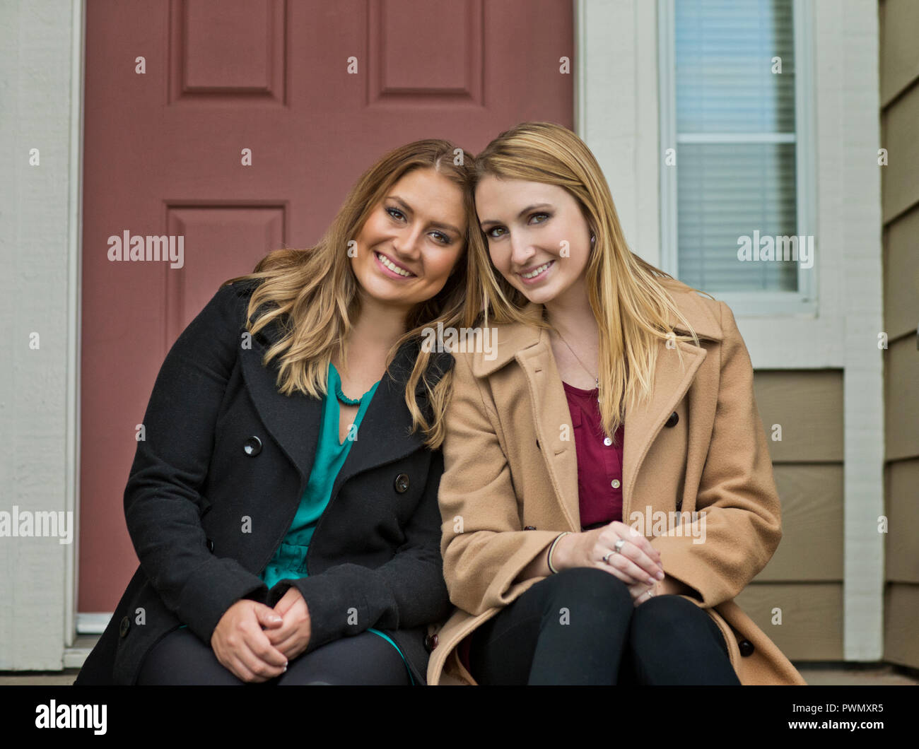 Portrait von zwei lächelnde junge Frauen auf der Veranda ihres Hauses sitzen. Stockfoto