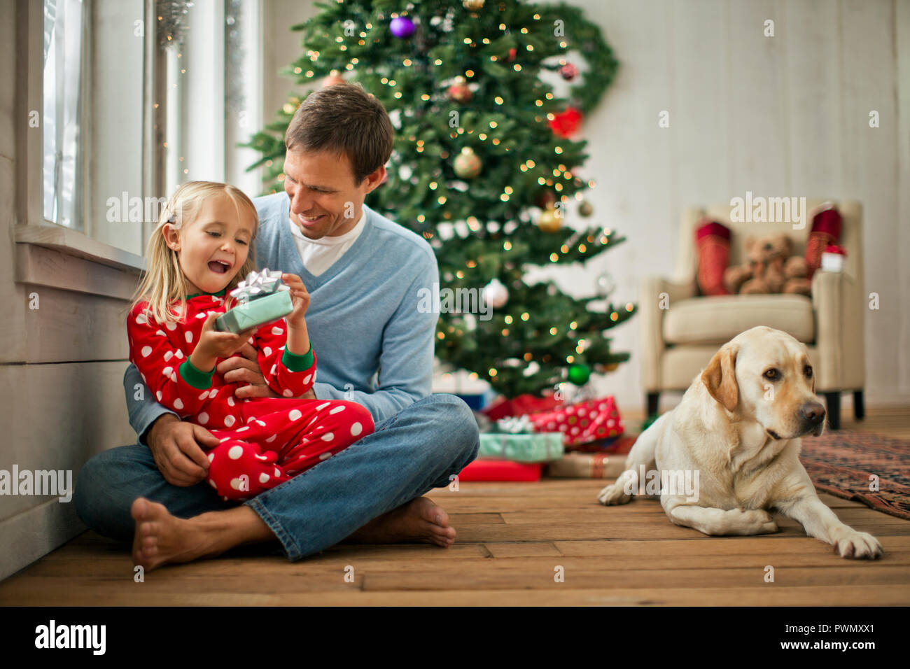 Vater und Tochter öffnen Geschenke zu Weihnachten. Stockfoto