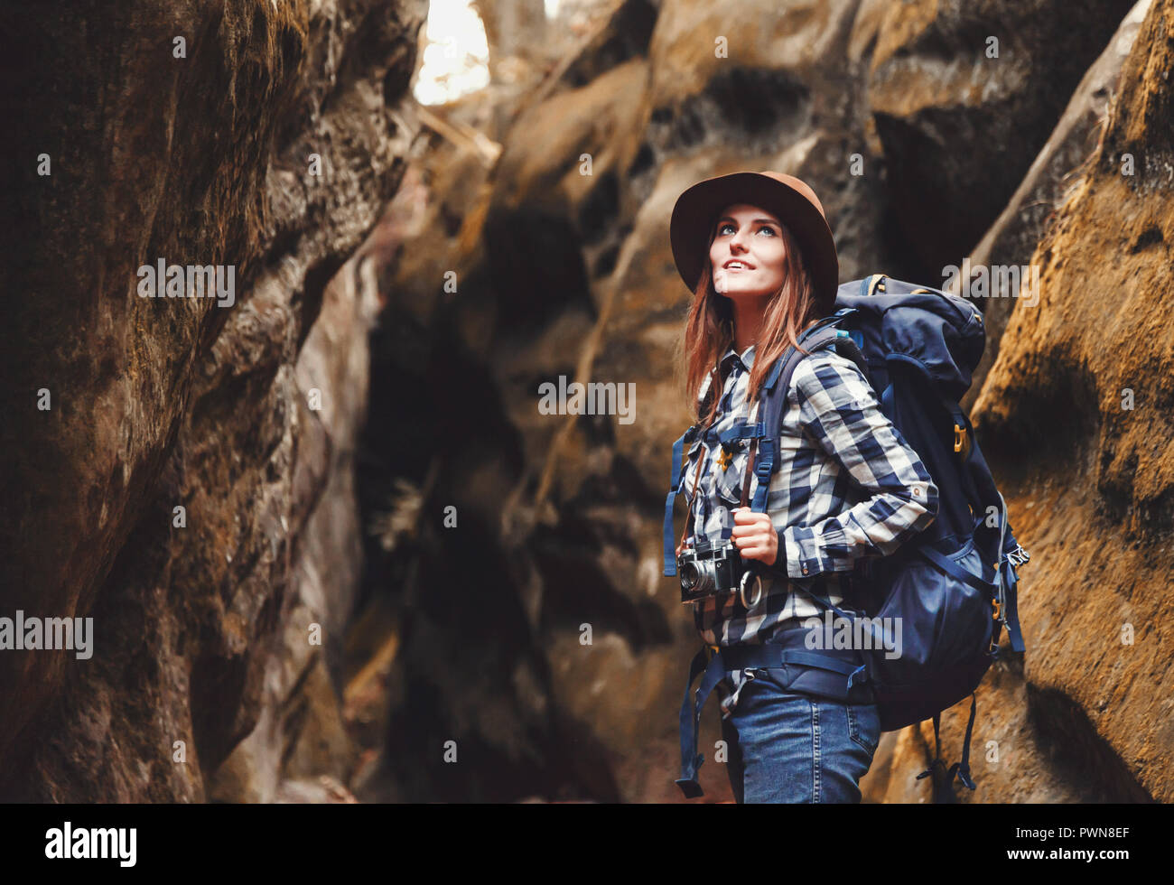 Reisen junge Frau mit braunen Hut, Plaid Shirt, Jeans und braune Stiefel  mit Rucksack wandern im Canyon mit Moos auf Steinen nach dem Wandern,  Konzept reisen Stockfotografie - Alamy