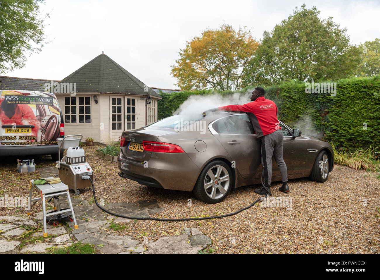 Mann mit einem mobilen Dampfreinigung Maschine ein luxuriöses Auto auf einer Startseite, Parkservice, England Großbritannien zu reinigen Stockfoto