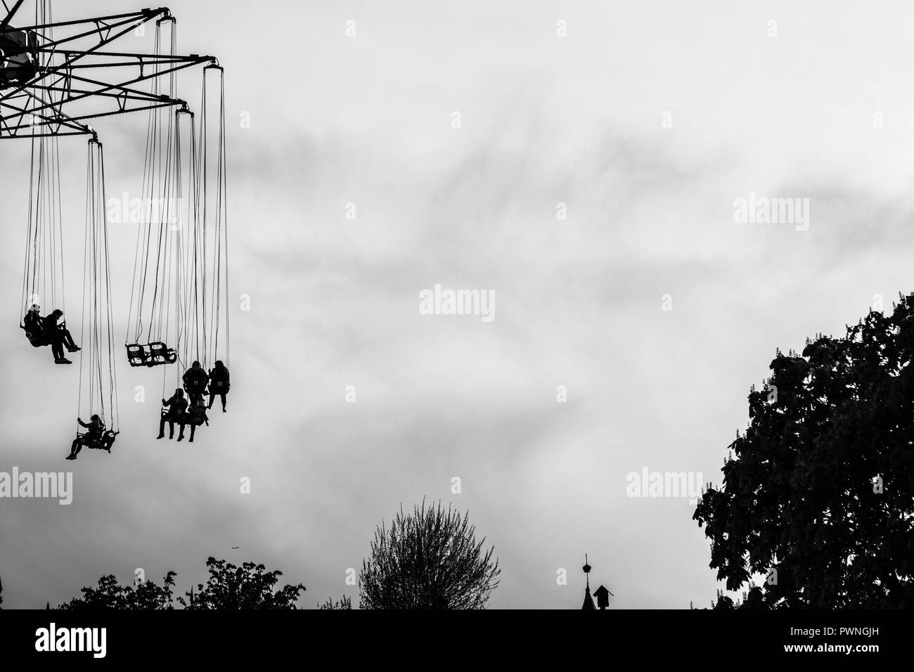 Silhouetten, die auf Swing Karussell in schwarzen und weißen Hintergrund Stockfoto