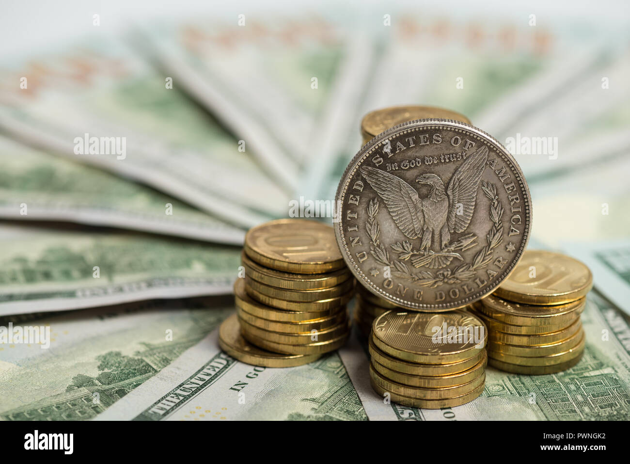 Anlagekonzept - Alte Silver Dollar Münze auf US-Dollarnoten und Haufen von goldenen Münzen Stockfoto