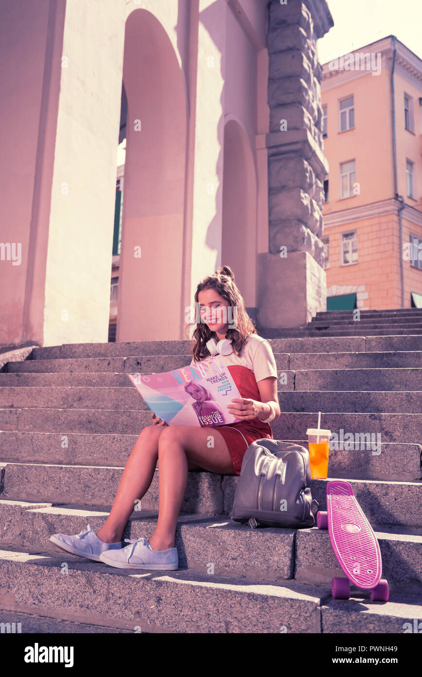 Strahlende junge Frau ihr Wochenende genießen mit Magazin und Sommer cocktail Stockfoto