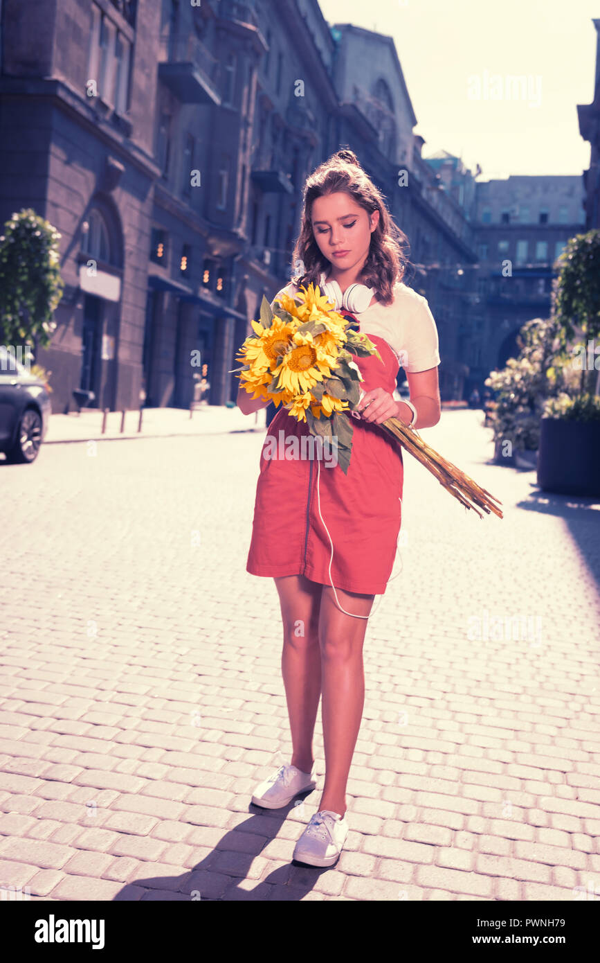 Curly dunkelhaarige Frau nach Hause gehen mit schönen hellen Sonnenblumen Stockfoto