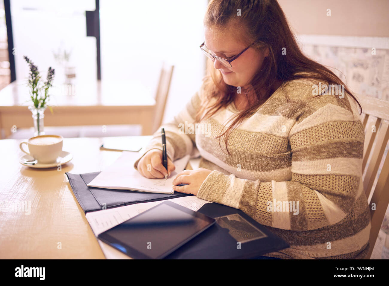 Angetrieben Plus size Business woman arbeitet am frühen Morgen an Ihrem lokalen Coffee Shop, mit einer warmen Tasse cappachino Ihr mit der Energie, die st geben Stockfoto