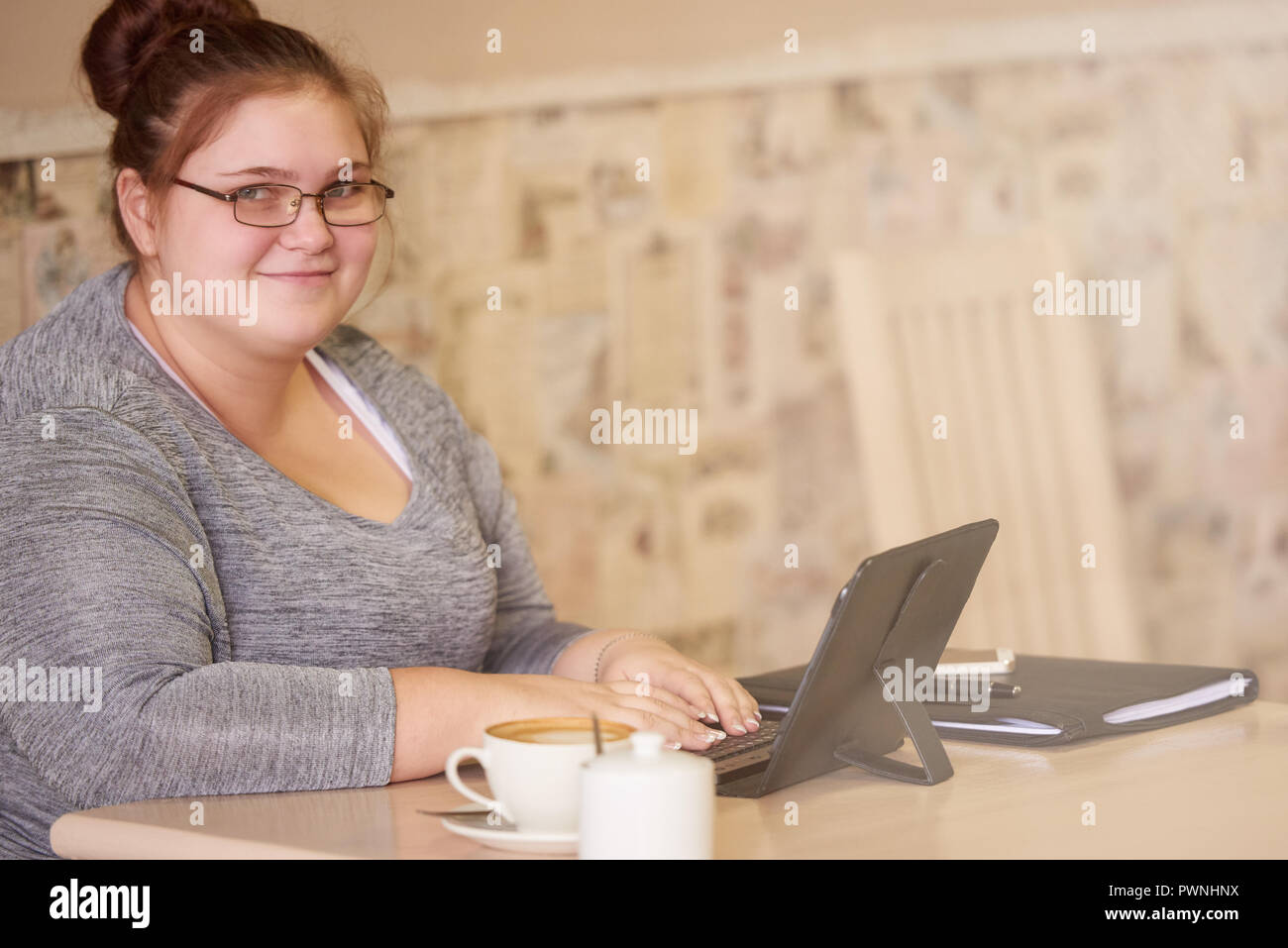 Schöne junge erwachsene Frau in die Kamera lächelnd mit den Händen des Einstiegschwellers auf der Tastatur nach dem spielabbruch in der Kamera mit einem subtilen Lächeln zu sehen Stockfoto