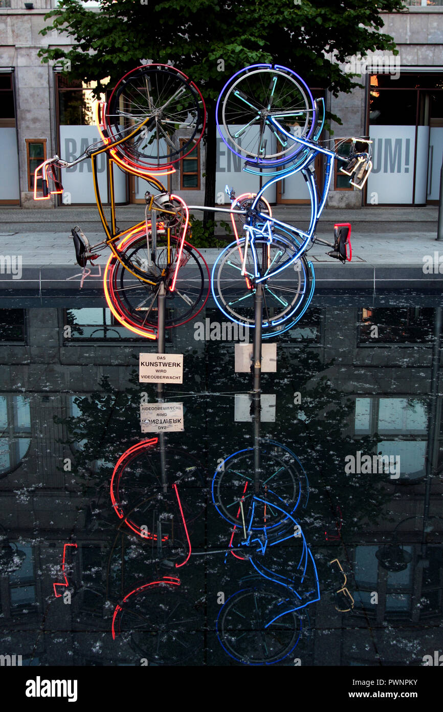 Zwei neon Fahrräder reflektieren sich in einem Teich als Kunstwerk in Berlin, Deutschland. Stockfoto