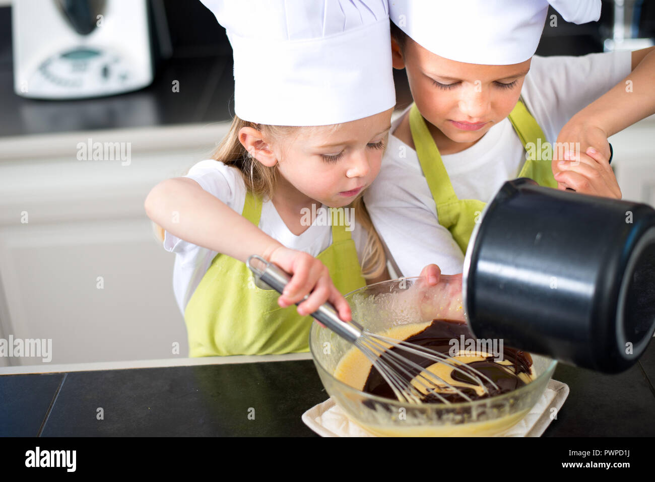 Zwei junge Kinder glückliche Kinder, Junge und Mädchen Familie mit Schürze und Koch hat die Vorbereitung lustig Cookies in der Küche zu Hause. Stockfoto