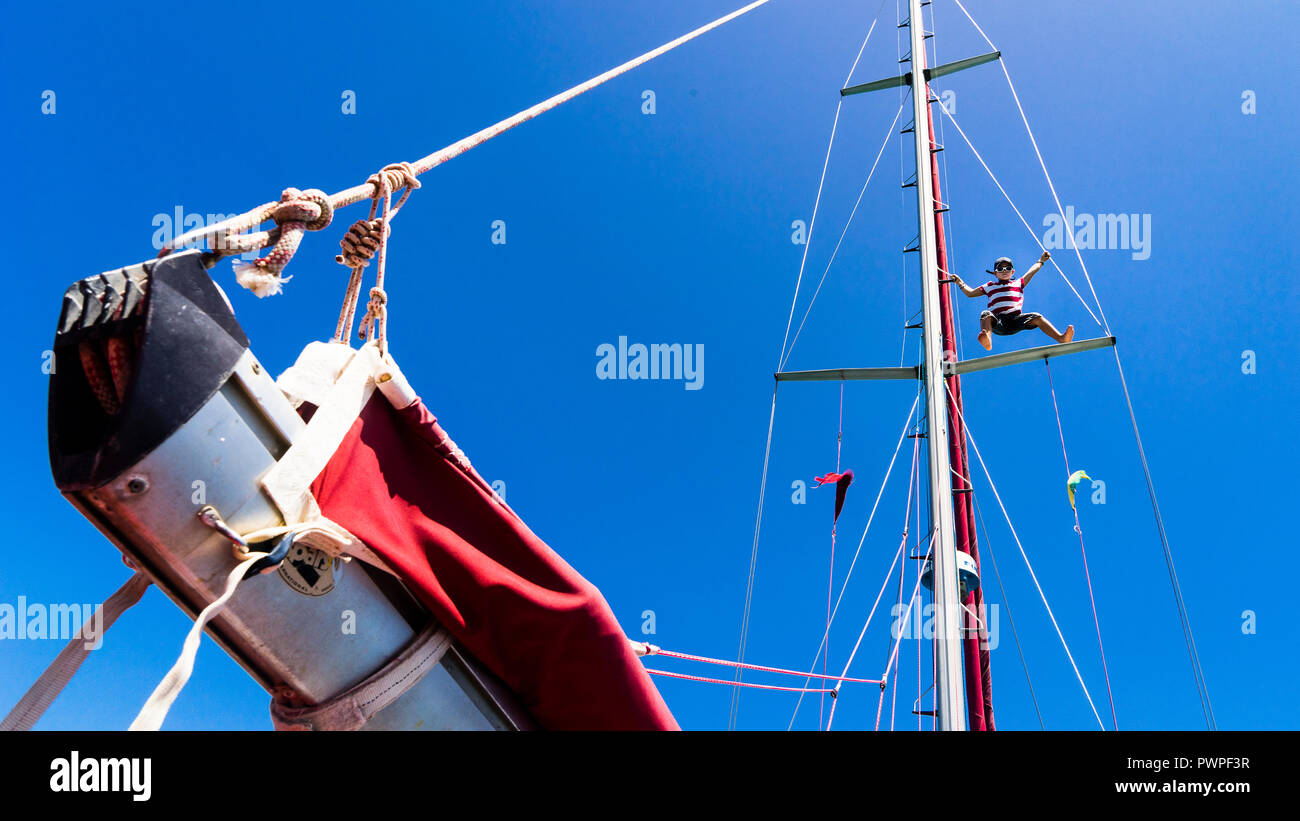 Ein Kind 7 Jahre alt, Klettern in einem Mast auf einem Segelboot, Clifton, Union Island, Kleine Antillen, Westindien Stockfoto
