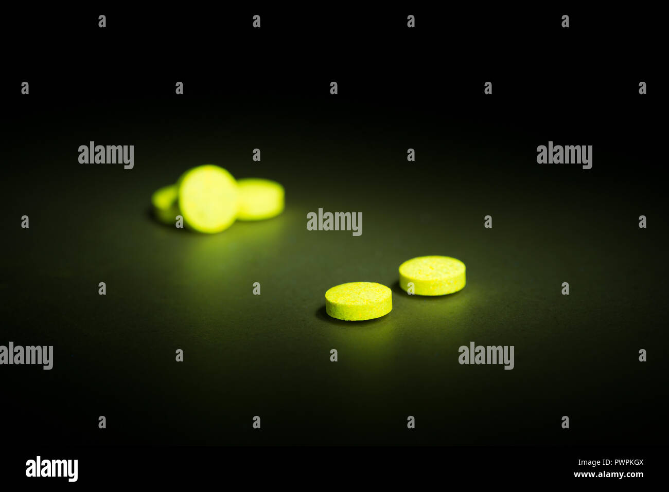 Glühende Vitamin B-Komplex Pillen und Tabletten fluoreszierende sichtbar gelbe Licht in Berührung gekommen Schwarzlicht Leuchten in der Finsternis Stockfoto
