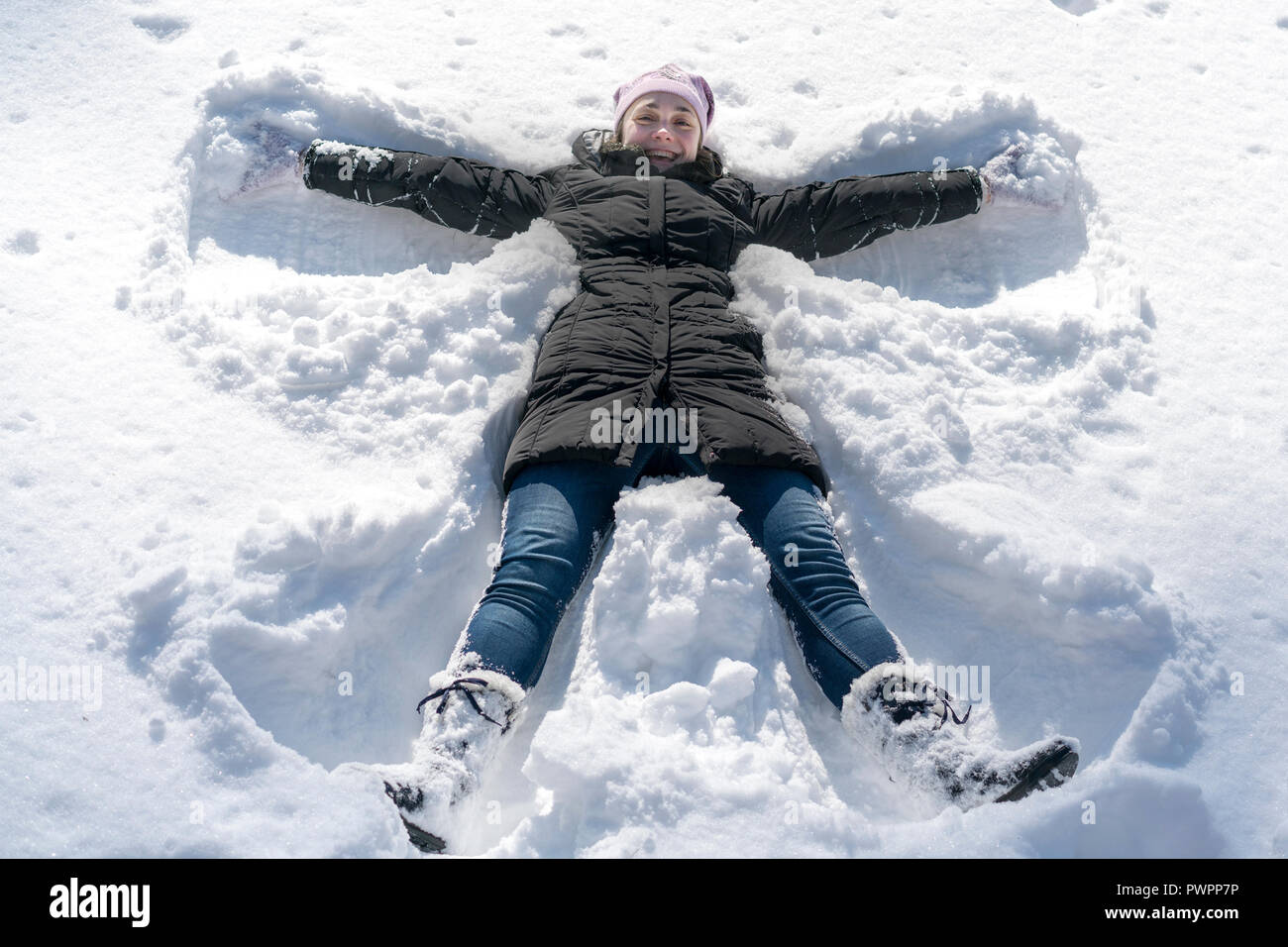 Glückliche junge Frau liegend auf Snow Fell im Winter. Junge Frau Scherz auf Schnee im Winter. Stockfoto