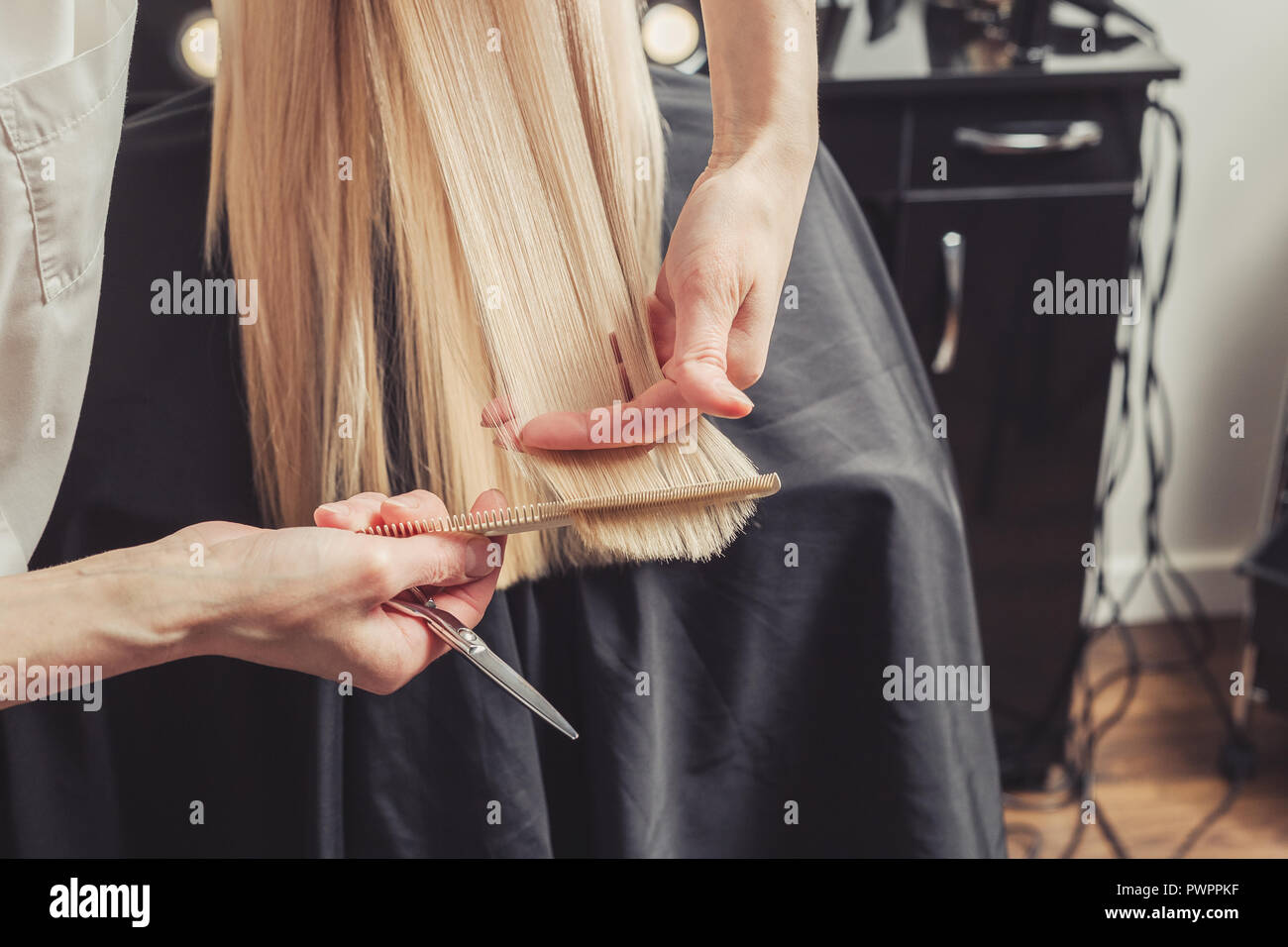 Friseur schneidet lange blonde Haare im Friseursalon Stockfoto