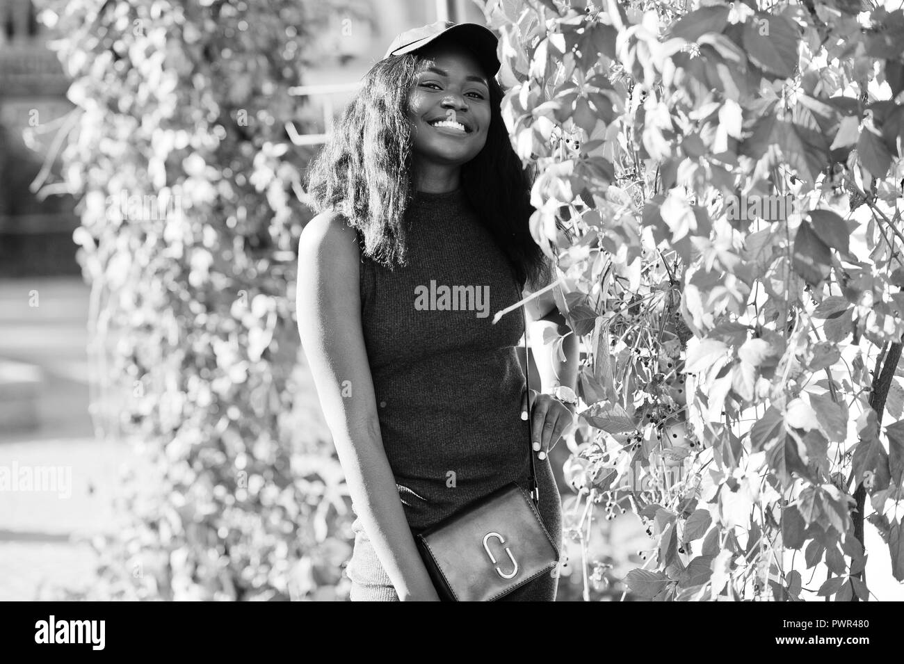 Stilvolle African American Girl in der Kappe an sonnigen Herbst Tag gegen rote Blätter. Afrika Modell Frau. Stockfoto