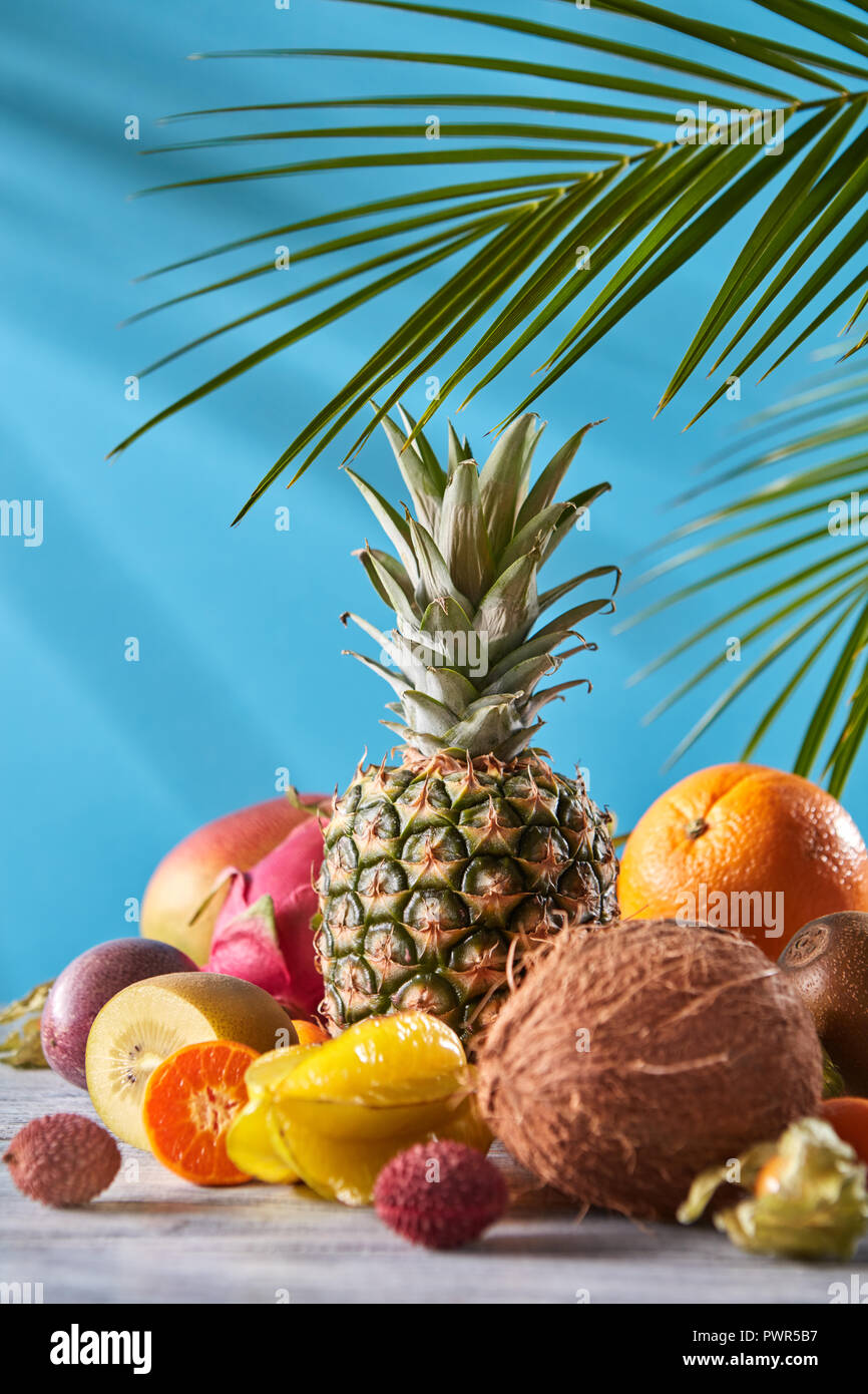 Exotischen Mix aus Reifen frischen Früchten - pineaple, Drachenfrucht, Mango, Kokos, Kiwi, Karambolen, Litschi auf grauem Stein Tabelle auf einem Blau. Stockfoto