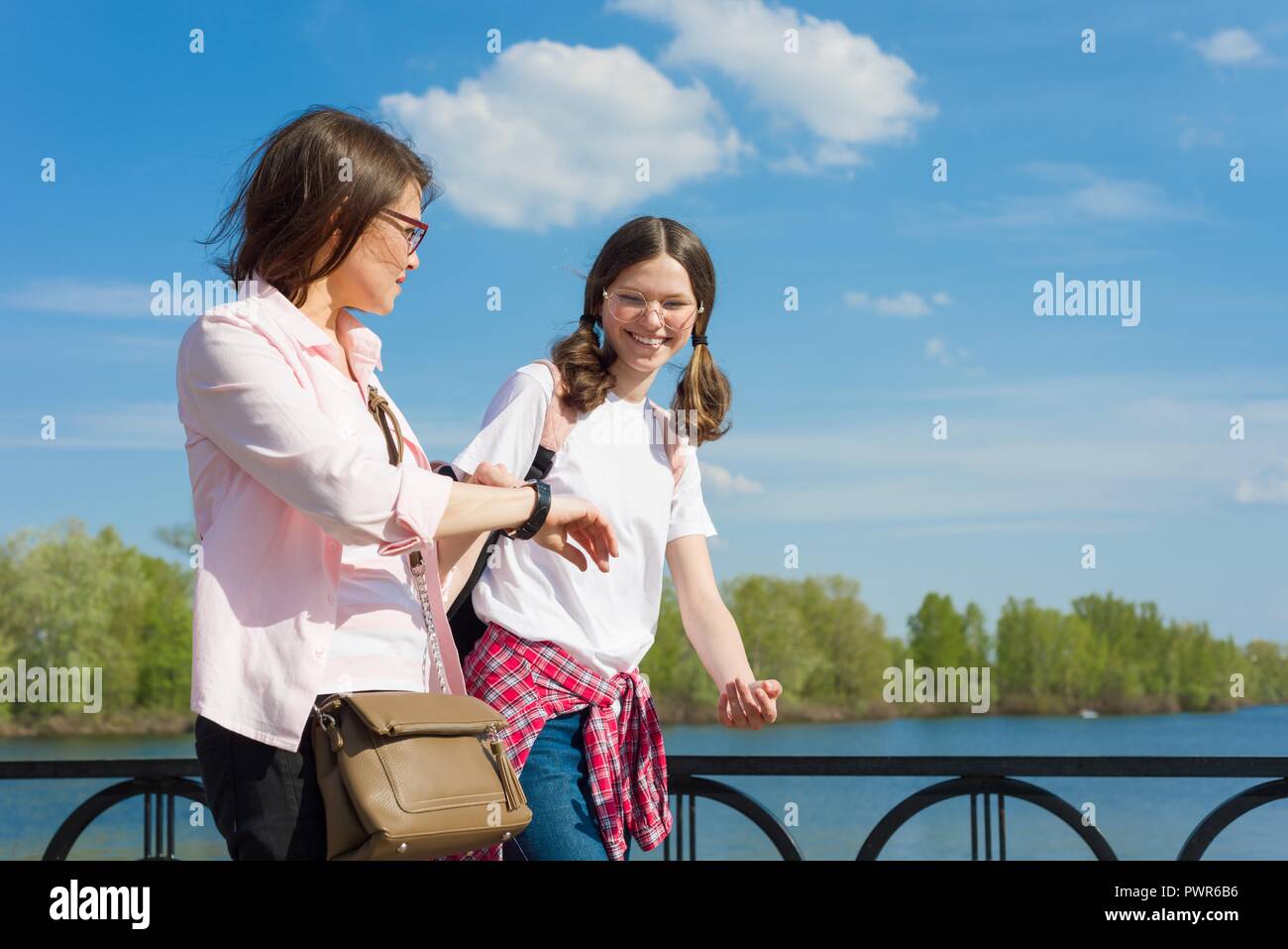 Mutter und Tochter Jugendlicher zu Fuß die Straße runter, die Frau sieht auf die Uhr, Binsen, ist spät, schnell geht. Stockfoto