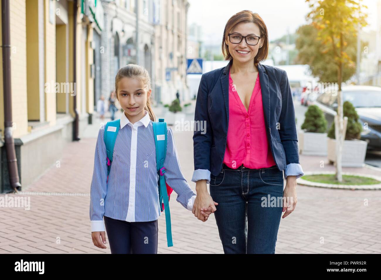 Mutter und Tochter halten sich an den Händen. Die Mutter nimmt das Kind in die Schule. Im Freien, kehren Sie in das Konzept der Schule. Stockfoto