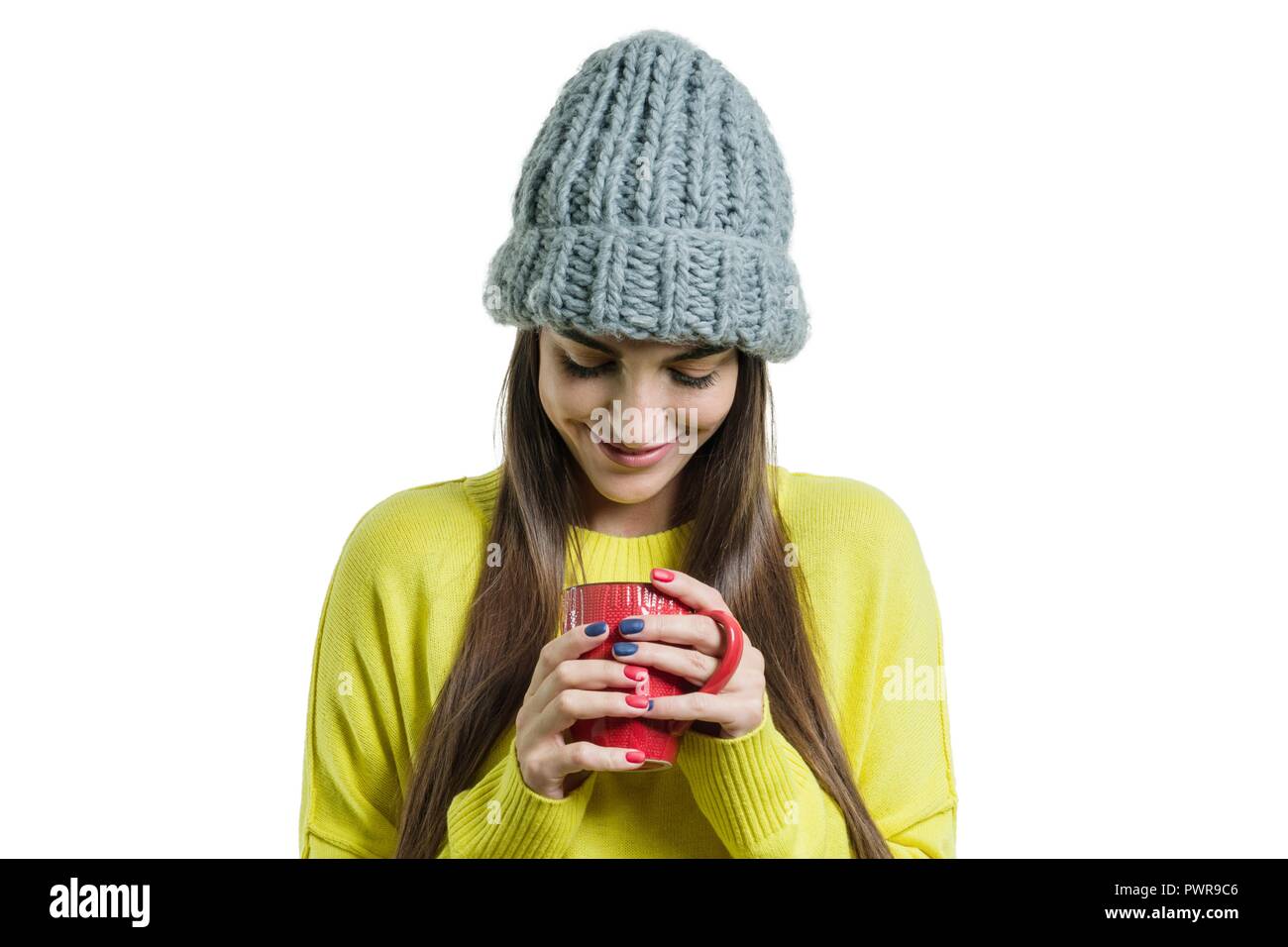 Portrait von Mädchen in gelb Pullover und gestrickte Mütze mit Schale in der Hand, eine Frau in den Becher suchen, weißem Hintergrund. Stockfoto