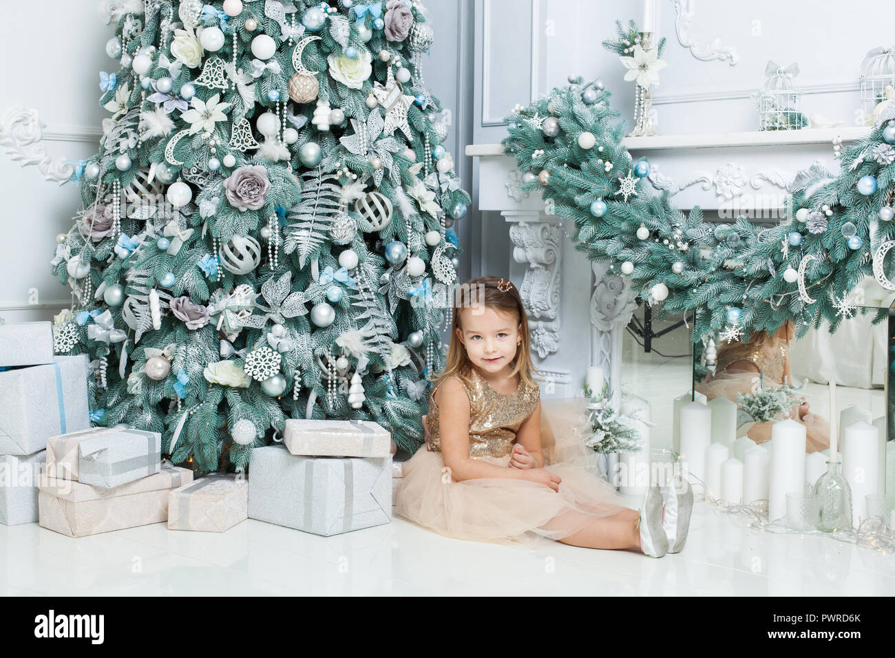 Kleines Mädchen in der Nähe der Weihnachtsbaum im Zimmer posieren. Stockfoto