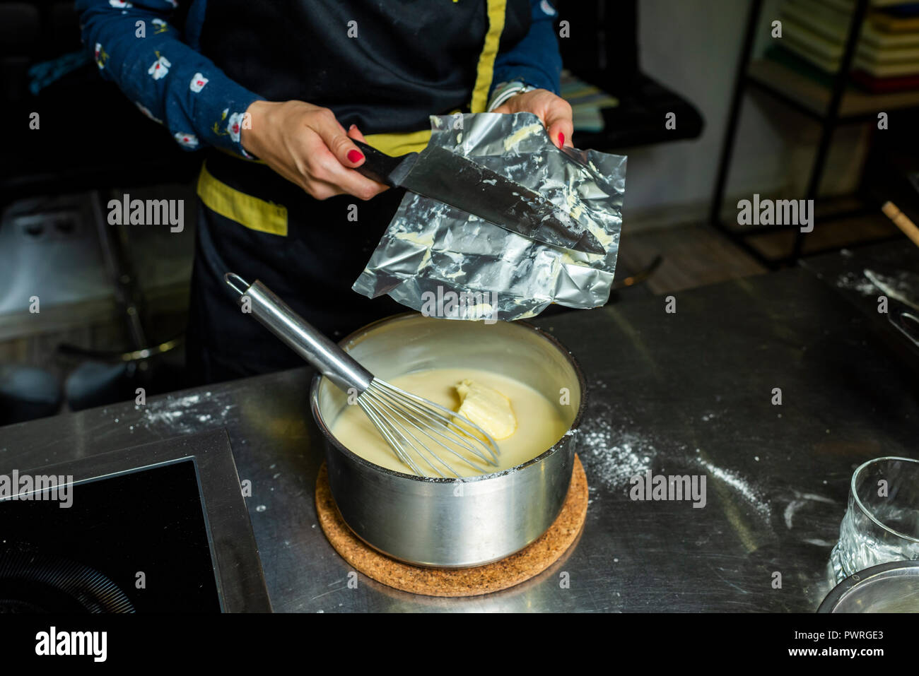 Hinzufügen von Butter von einer Packung zu einer Creme von Hand gefertigt Stockfoto