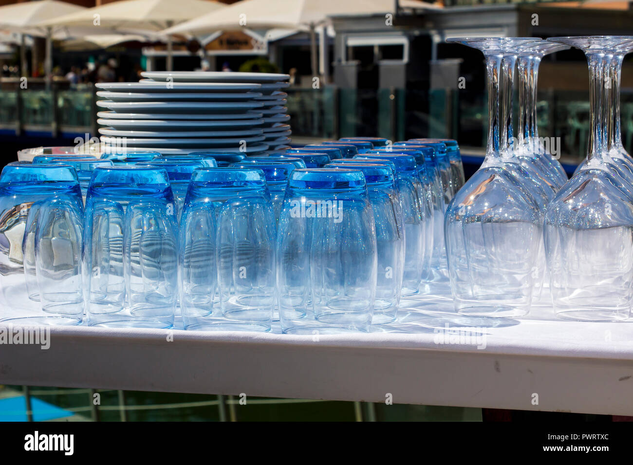 Blau getönte Gläser und Weingläser mit Platten in einem Restaurant am Yachthafen von Vilamoura Portugal gestapelt Stockfoto
