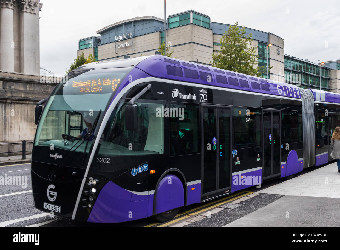 Gleitschirm-Bus von der Bushaltestelle mit Laganside Gerichte im Hintergrund ziehen. Neue gelenkbusse, die Ost und West Belfast eingeführt von Translink Stockfoto
