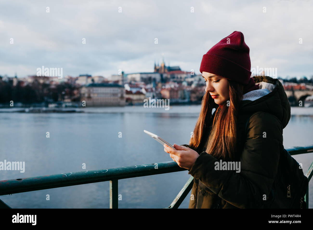 Ein Mädchen auf der Straße in Prag bei Sonnenuntergang verwendet eine Tablette, um die Karte oder das Internet anzuzeigen oder eine mobile Anwendung verwenden. Stockfoto