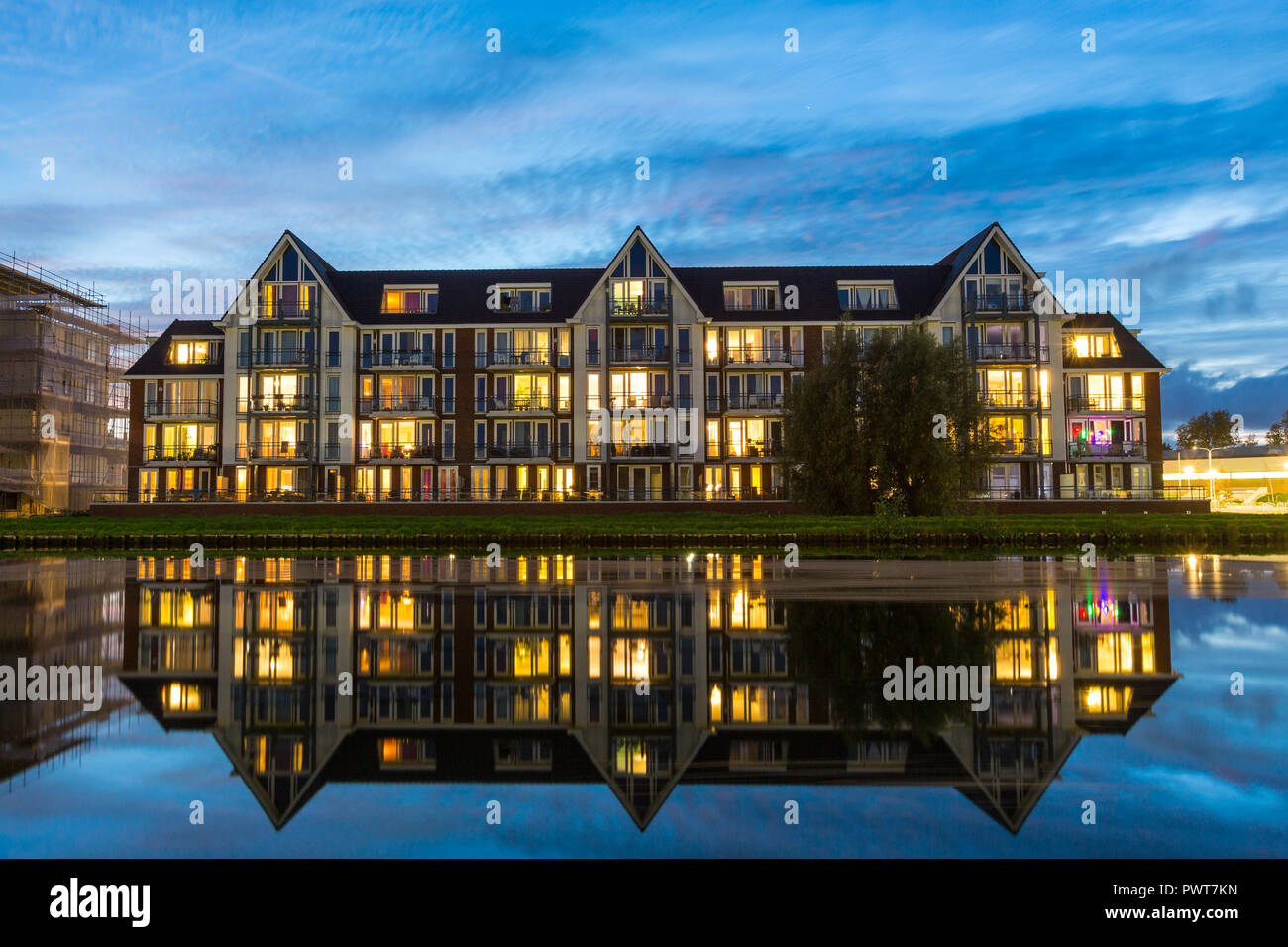 Reflexionen in einen Kanal eines modernen Wohnungen Gebäude mit bunten Lichter während der Blauen Stunde in Suburban Area in Holland. Stockfoto